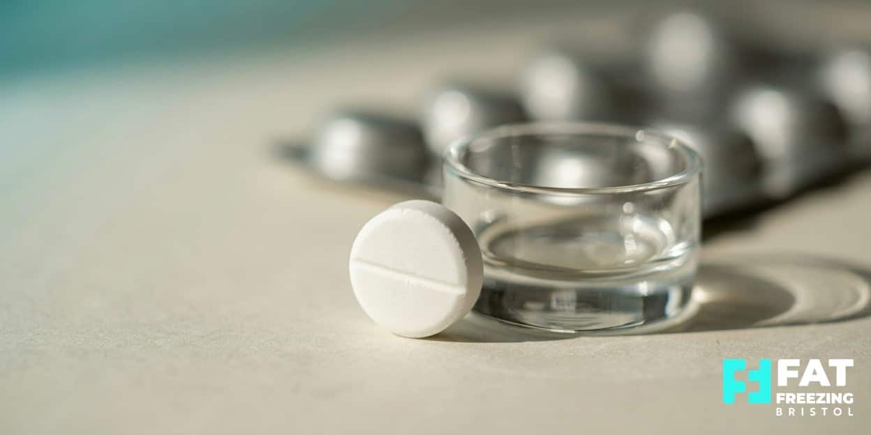 Macro photograph of a single oral semaglutide tablet beside a glass of water with a blurred blister pack, showing the GLP-1 weight-loss pill approved in the UK